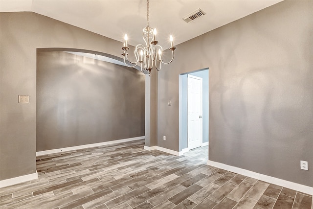 unfurnished dining area with hardwood / wood-style floors, a notable chandelier, and vaulted ceiling