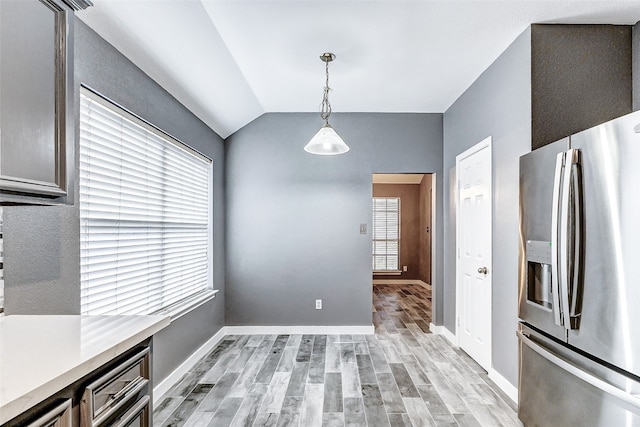 unfurnished dining area with lofted ceiling and light hardwood / wood-style flooring