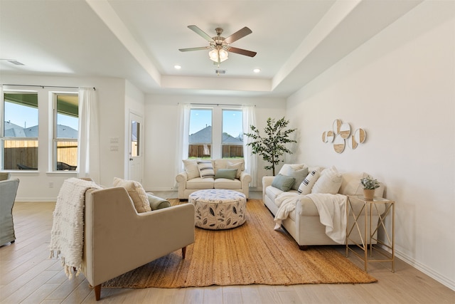 living room with light hardwood / wood-style flooring, ceiling fan, and a healthy amount of sunlight