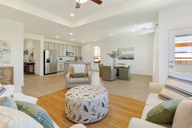 living room with a wealth of natural light, light hardwood / wood-style flooring, and ceiling fan