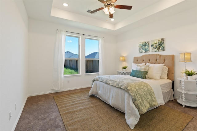 carpeted bedroom with a raised ceiling and ceiling fan