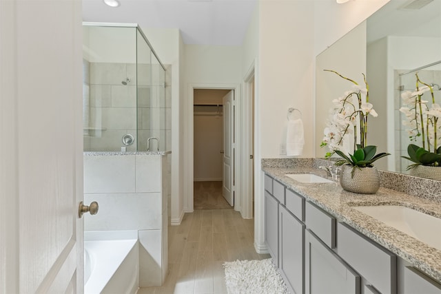 bathroom with hardwood / wood-style flooring, vanity, and shower with separate bathtub