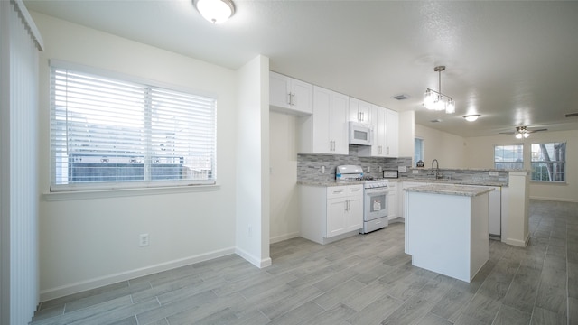 kitchen featuring kitchen peninsula, white appliances, a kitchen island, pendant lighting, and white cabinetry