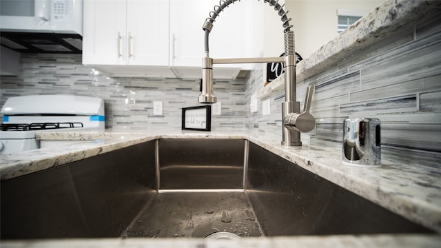 kitchen featuring white cabinetry, light stone countertops, and backsplash