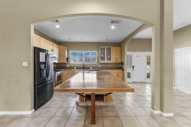 kitchen with a center island, light tile patterned floors, sink, and appliances with stainless steel finishes