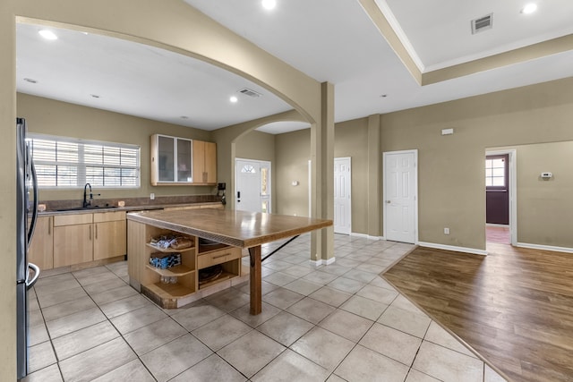 kitchen with sink, a center island, light hardwood / wood-style flooring, stainless steel fridge, and light brown cabinetry