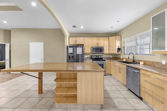 kitchen with stainless steel appliances, sink, light brown cabinets, light tile patterned floors, and a center island