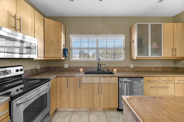 kitchen featuring light tile patterned flooring, sink, stainless steel appliances, and light brown cabinets