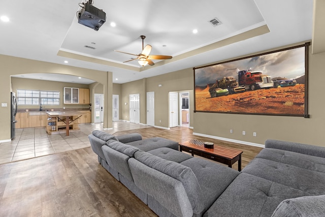 living room with a tray ceiling, ceiling fan, hardwood / wood-style floors, and sink