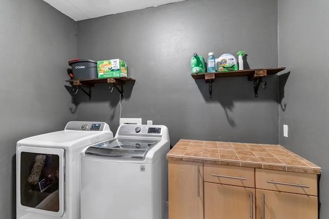 laundry area featuring separate washer and dryer and cabinets