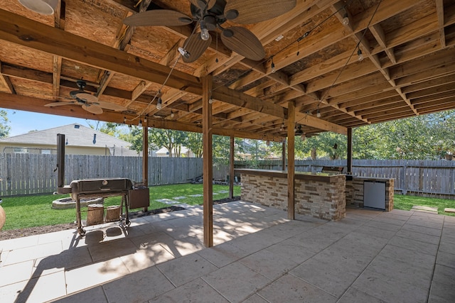 view of patio with exterior bar, ceiling fan, and exterior kitchen