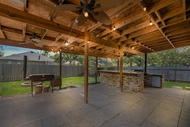 view of patio with a bar, ceiling fan, and exterior kitchen