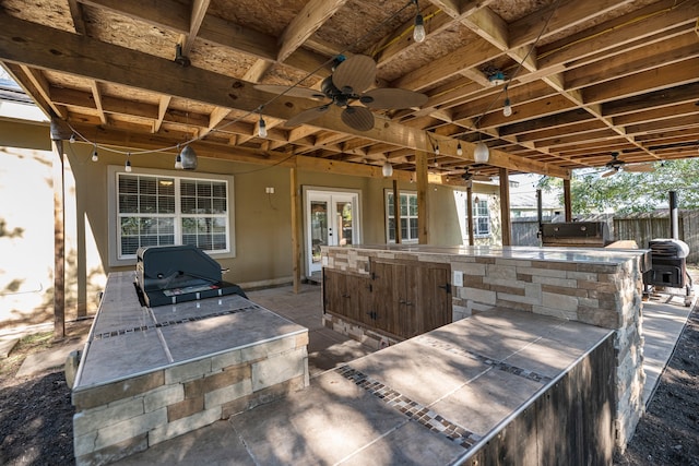 view of patio featuring ceiling fan, french doors, an outdoor bar, and an outdoor kitchen