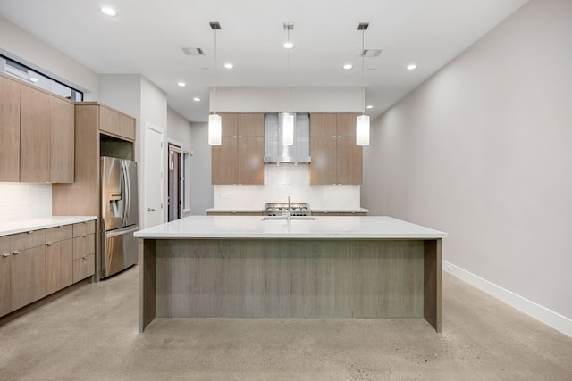 kitchen featuring stainless steel refrigerator with ice dispenser, tasteful backsplash, wall chimney exhaust hood, pendant lighting, and a center island with sink