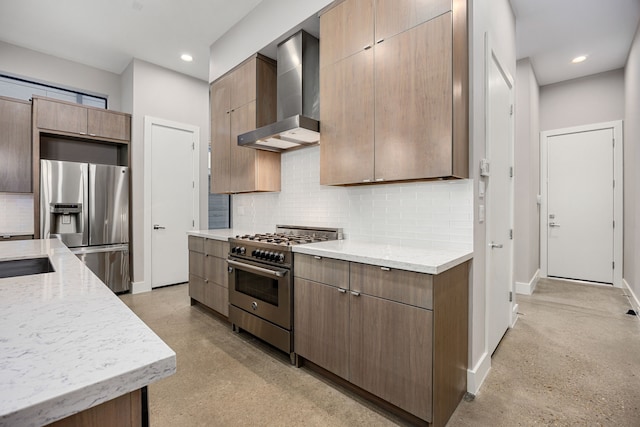 kitchen with backsplash, light stone counters, wall chimney range hood, and appliances with stainless steel finishes