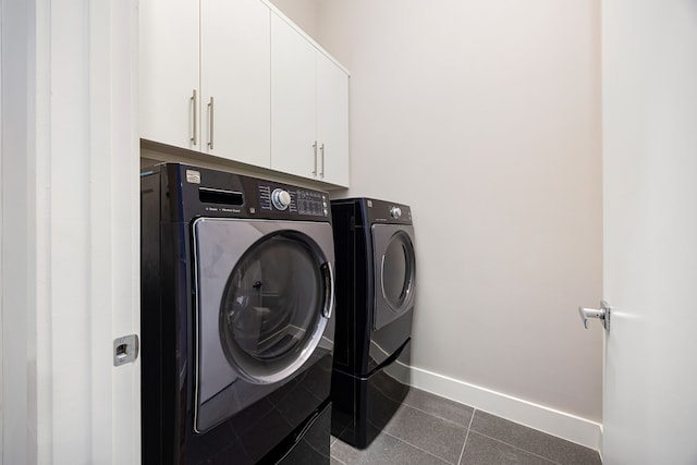 laundry room featuring dark tile patterned flooring, cabinets, and separate washer and dryer