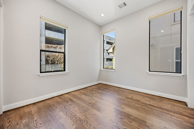 empty room with hardwood / wood-style floors and a healthy amount of sunlight