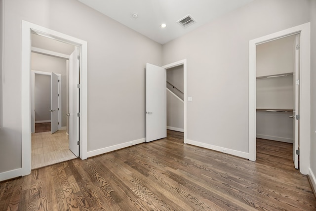 unfurnished bedroom featuring hardwood / wood-style flooring, a spacious closet, and a closet