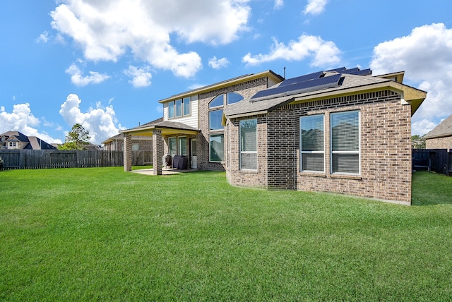 back of property featuring a lawn, solar panels, and a patio area