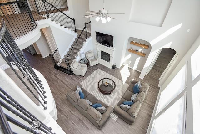 living room featuring ceiling fan, dark hardwood / wood-style flooring, and a towering ceiling