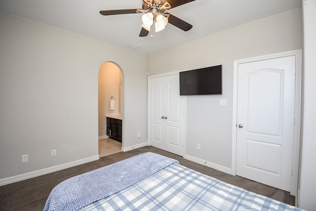 carpeted bedroom featuring ensuite bath, ceiling fan, and a closet