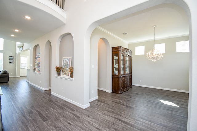 interior space with a notable chandelier, dark hardwood / wood-style flooring, and ornamental molding