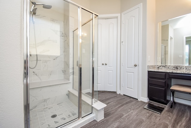 bathroom with hardwood / wood-style floors, vanity, and a shower with shower door