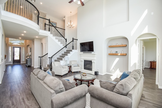 living room featuring dark hardwood / wood-style floors, ceiling fan with notable chandelier, and a high ceiling