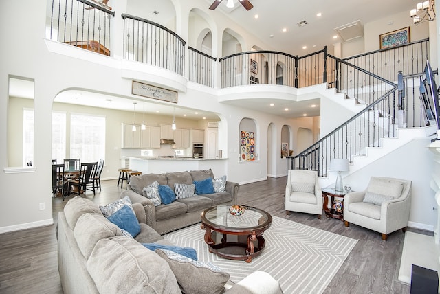 living room featuring ceiling fan, a towering ceiling, and dark wood-type flooring