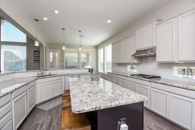 kitchen with a kitchen island, white cabinetry, sink, and a breakfast bar area