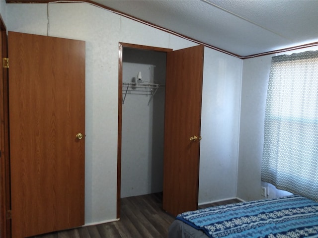 bedroom with a textured ceiling, dark hardwood / wood-style flooring, and a closet