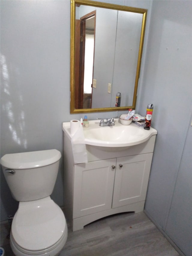 bathroom with wood-type flooring, vanity, and toilet