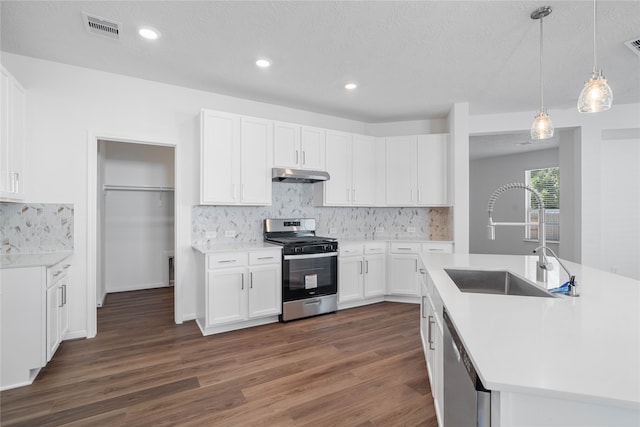 kitchen with appliances with stainless steel finishes, a textured ceiling, dark hardwood / wood-style floors, and white cabinetry