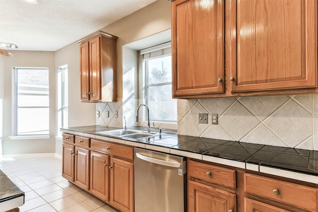 kitchen featuring sink, tasteful backsplash, stainless steel dishwasher, tile countertops, and light tile patterned floors