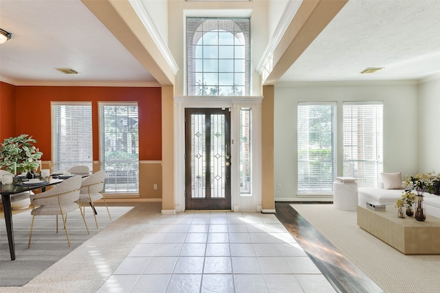 entrance foyer with a healthy amount of sunlight, ornamental molding, and light tile patterned floors