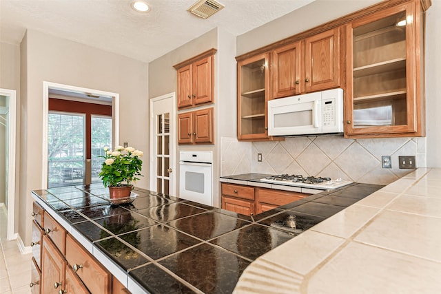 kitchen with tasteful backsplash, tile countertops, a textured ceiling, and white appliances