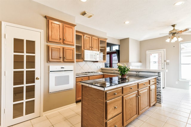 kitchen with tile counters, white appliances, a wealth of natural light, and tasteful backsplash