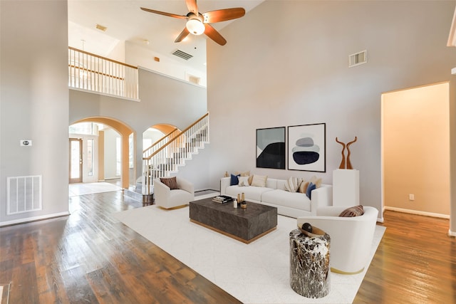 living room with a high ceiling, dark hardwood / wood-style floors, and ceiling fan