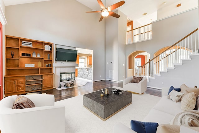 living room featuring plenty of natural light, a fireplace, hardwood / wood-style floors, and a high ceiling