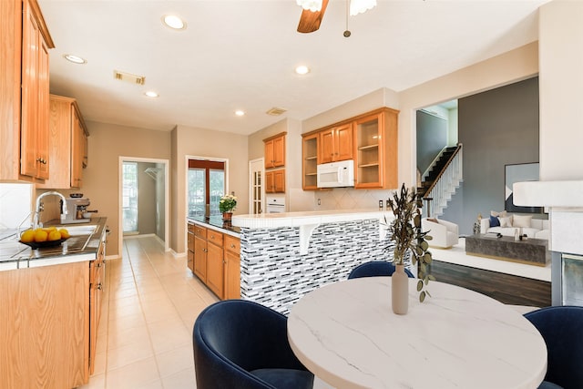 kitchen with sink, ceiling fan, light tile patterned floors, tasteful backsplash, and kitchen peninsula