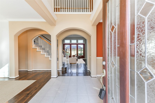 entryway with wood-type flooring, french doors, crown molding, and beam ceiling