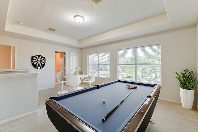 game room featuring a tray ceiling, a wealth of natural light, and light carpet