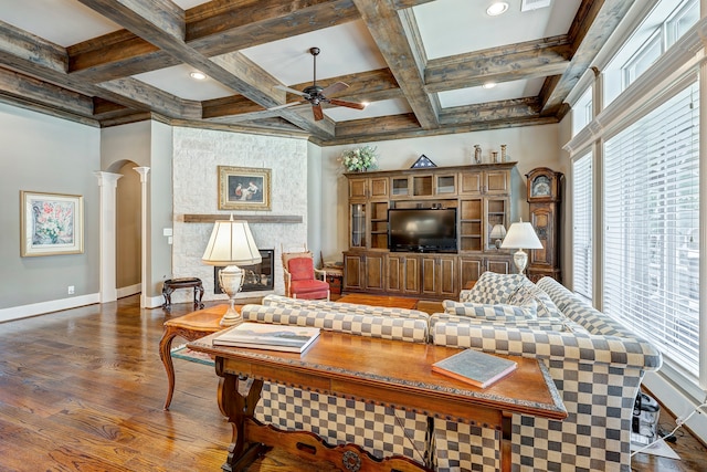 living room featuring beam ceiling, ornate columns, a large fireplace, dark wood-type flooring, and coffered ceiling