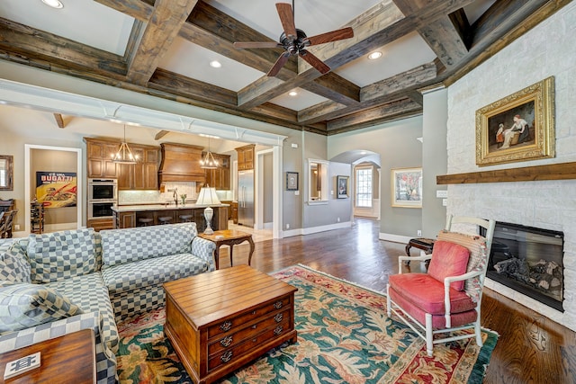 living room featuring coffered ceiling, dark wood-type flooring, sink, beam ceiling, and a fireplace