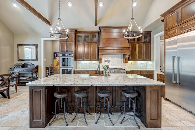 kitchen with stainless steel appliances, vaulted ceiling, a kitchen island with sink, sink, and pendant lighting