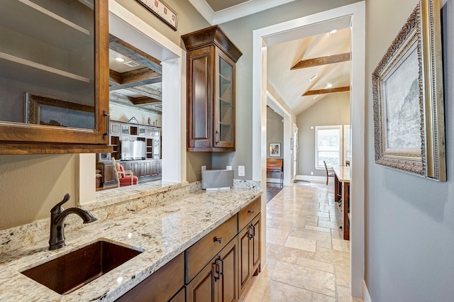 kitchen featuring beam ceiling, light stone countertops, sink, and ornamental molding