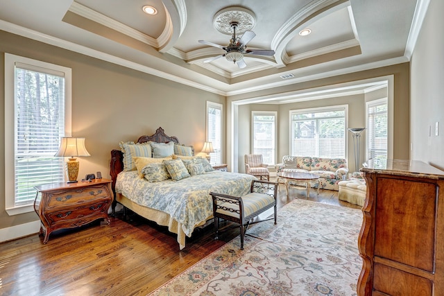 bedroom with a tray ceiling, ceiling fan, light hardwood / wood-style flooring, and ornamental molding