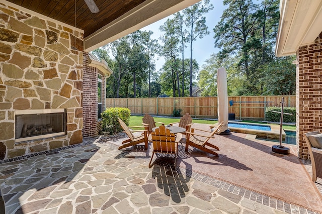 view of patio featuring an outdoor stone fireplace and a pool