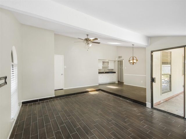 unfurnished living room featuring dark hardwood / wood-style floors, lofted ceiling, sink, and ceiling fan with notable chandelier