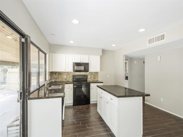 kitchen featuring sink, dark wood-type flooring, dark stone counters, white cabinets, and black appliances